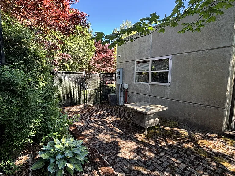 The "way back" patio is one of three spaces in the fenced back yard surrounded by trees and shrubs. Plenty of room for a large dining table, outdoor couch, lounge chairs, and plant pots.