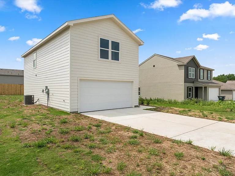 Two-story residence featuring light-colored siding, an attached garage, and a concrete driveway