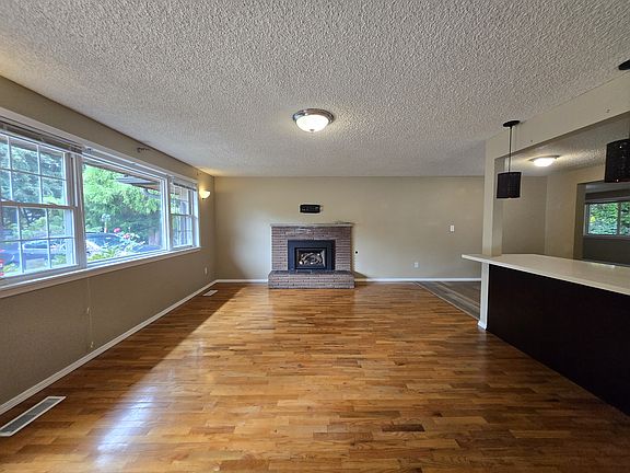 Living room has large picture window and gas burning fireplace. Original refinished hardwood floors.