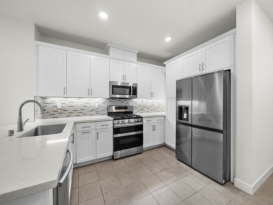 Open kitchen with quartz counter tops and stainless steel appliances, and brand new refrigerator.