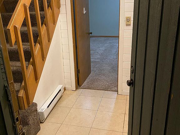 Tiled front entryway looking into downstairs bedroom