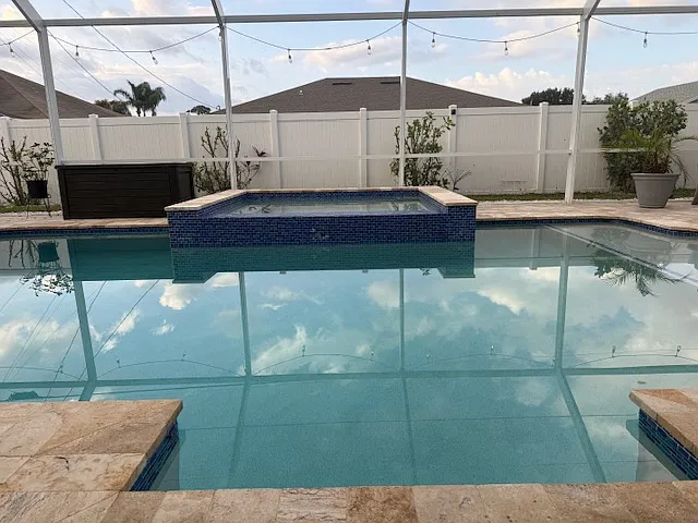 Sparkling screened-in pool with spa and private fenced backyard