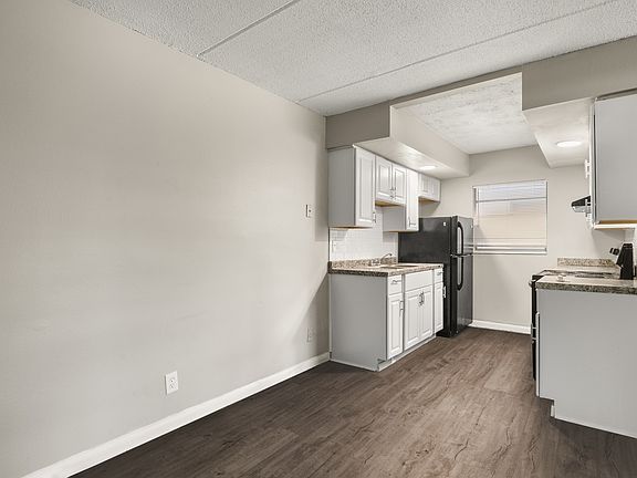 Contemporary kitchen with sleek white cabinets, modern appliances, and elegant countertop, set against stylish wood flooring.