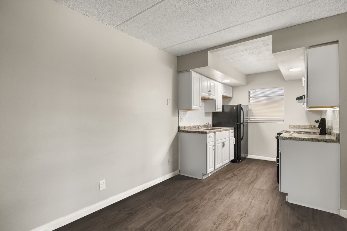Contemporary kitchen with sleek white cabinets, modern appliances, and elegant countertop, set against stylish wood flooring.