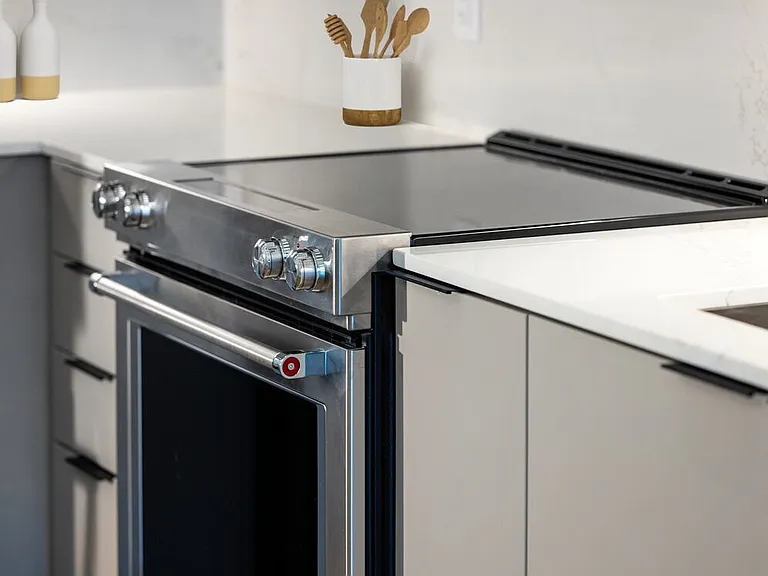 Signature Collection kitchen with light grey cabinetry, electric stove, and marbled quartz countertops and backsplash