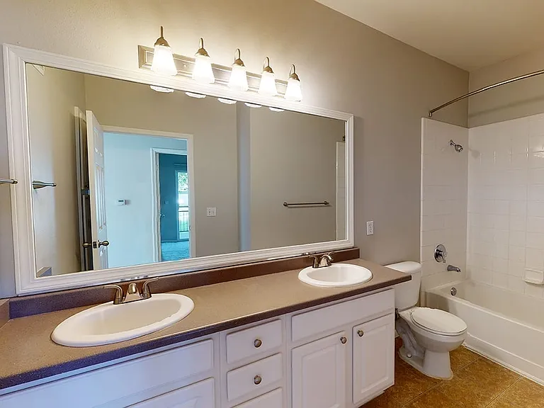 Apartment bathroom with large soaking tub, wood-style flooring and double sinks.