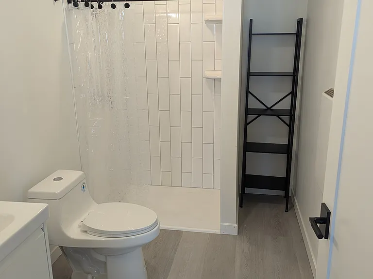Subway tile shower with matte black finishes and dual-flush toilet