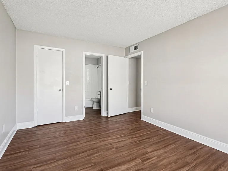 Bright bedroom featuring wood-style flooring and convenient access to the bathroom and closet.
