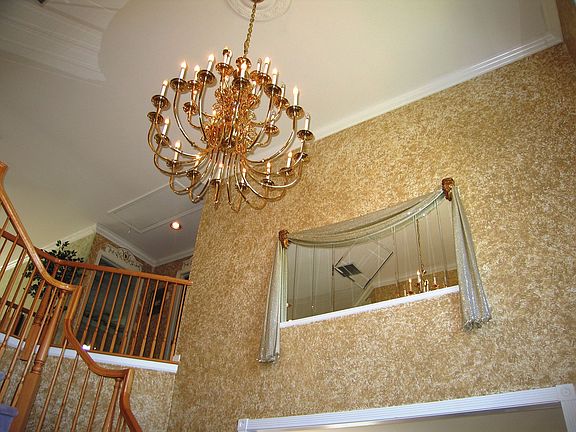 View the foyer adorned with mirrors, gold trimming decor and hardwood floors.