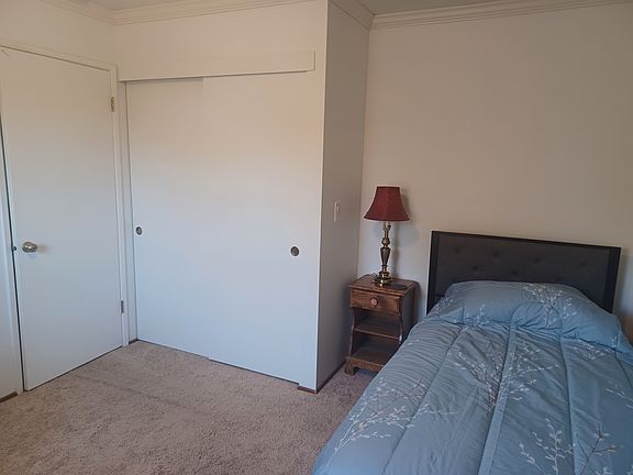bedroom (closet view), twin bed, side table. Note* new carpet has been installed.