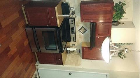 Electric Range with vent hood and wood cabinetry.