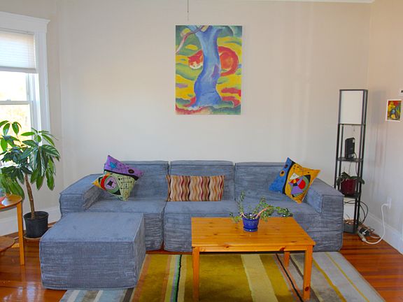 Sunny, cosy living room updated 2025 with powerful window-mounted cooling & new couch. Overlooks ball park and features bay windows, & polished wooden floors.