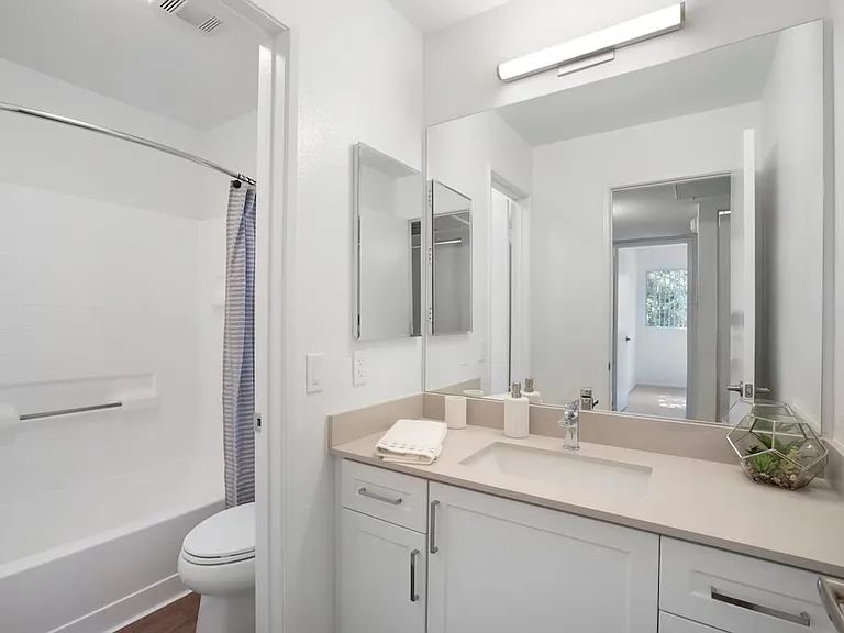 Renovated Package I bath with light grey quartz countertops, white cabinetry, and hard surface flooring