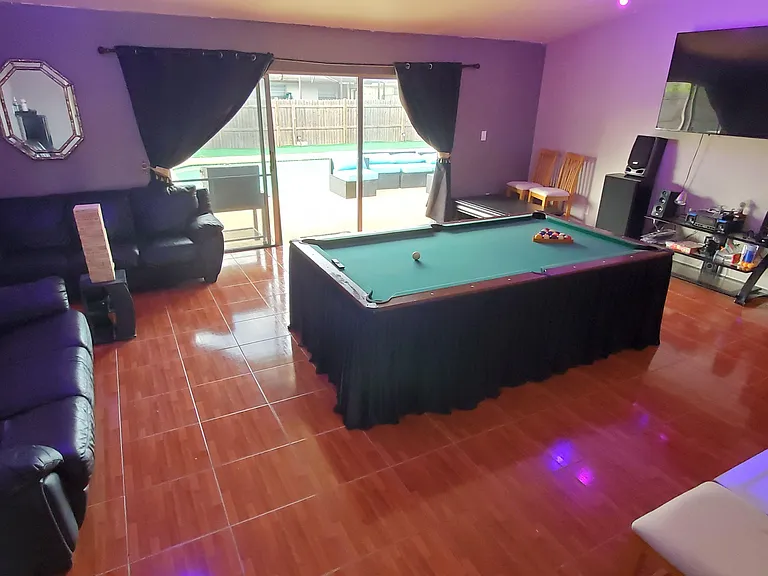 Entertainment-focused living area with a pool table, sectional seating, and large TV, plus sliding doors to the patio.