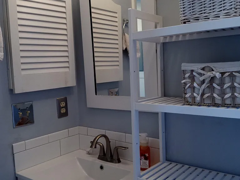 The bathroom has a built in medicine cabinet with shelves and more storage in the vanity cabinet.