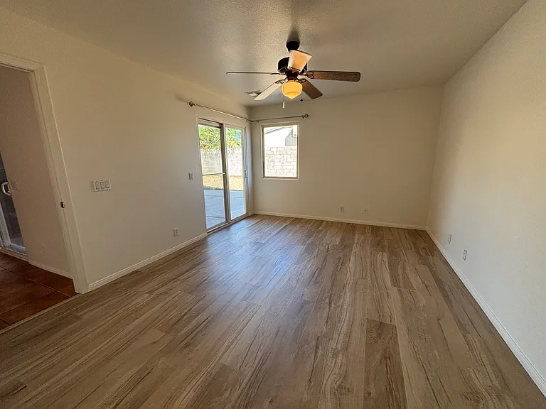 Spacious bedroom with ceiling fan, durable flooring, and direct access to the backyard.
