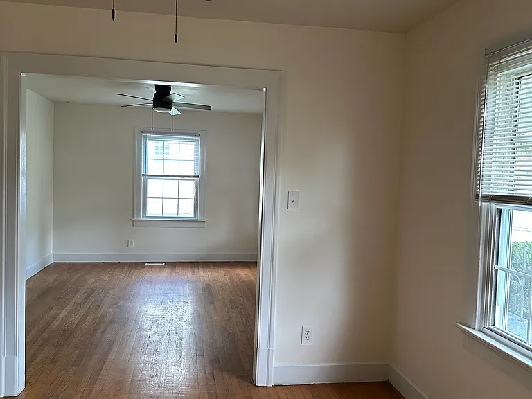 Dining area looking into living room. Both with hardwood flooring and new ceiling fans.