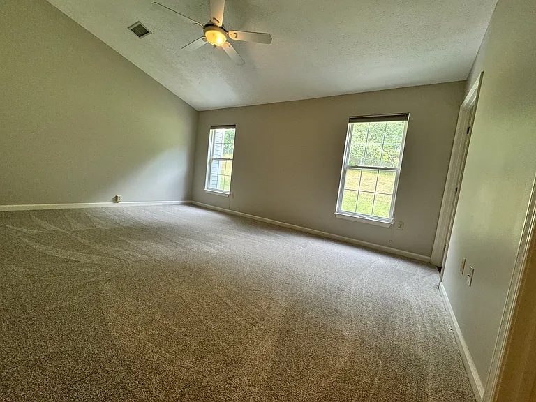 Spacious master bedroom with vaulted ceilings and a ceiling fan