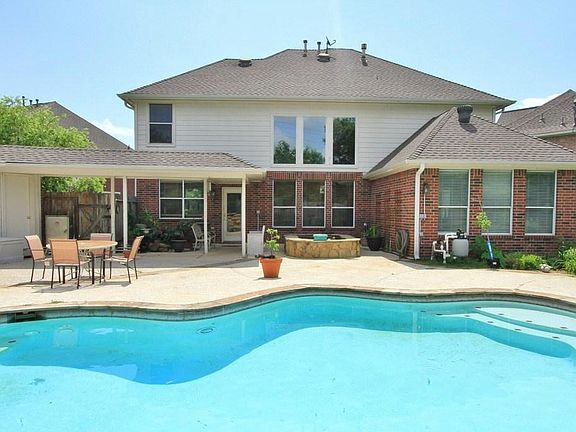 Looking towards the Back of the Home shows how there's lots of pool decking and a partial covered pa