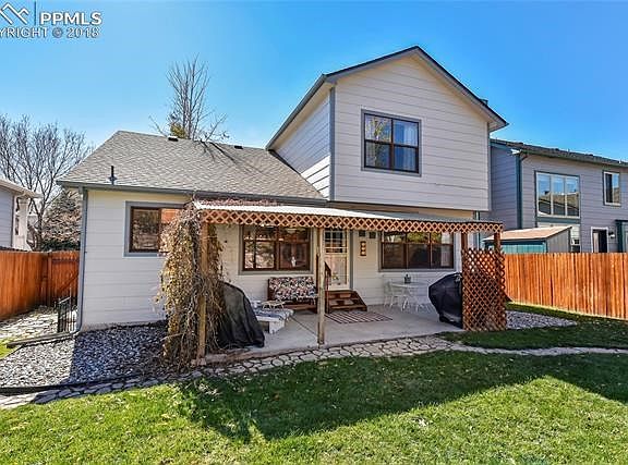 Covered concrete patio with grape vines for privacy on one side.