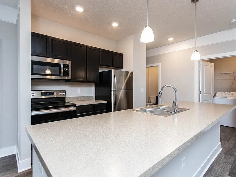 Dooley's Orchard updated kitchen unit showing a countertop, stovetop, oven, microwave, and refrigerator, with a washer dryer nearby.