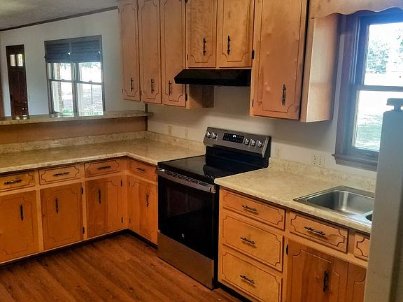 Kitchen with new GE stove/oven and hood. View to the living room area, ceiling fan and front door to the home.