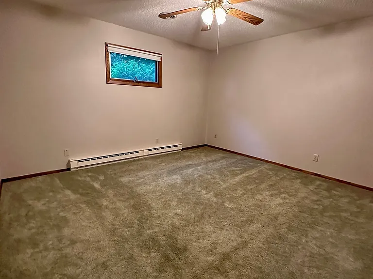 Spacious primary bedroom featuring neutral walls, natural light from window, and full walk-in closet. The room offers ample space for a queen or king-sized bed along with additional furniture.