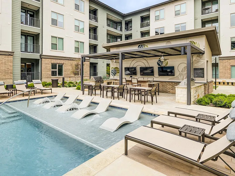 Poolside Dining Tables and Chaise Lounges Beside In-Water Loungers
