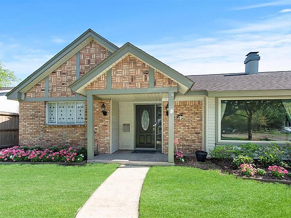 Close up view of inviting front porch with lead glass front door. Notice blooming flowers. Home has a 4-zone RainBird sprinkler system in front yard.
