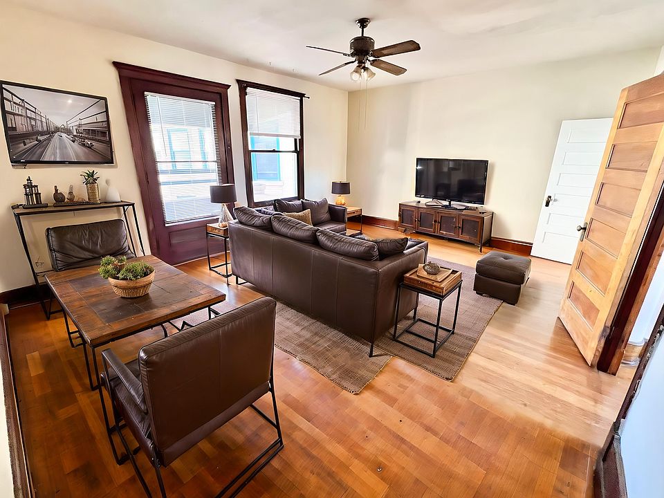 Charming and cozy living room with elegant hardwood floors, plush leather seating, and a modern entertainment center.