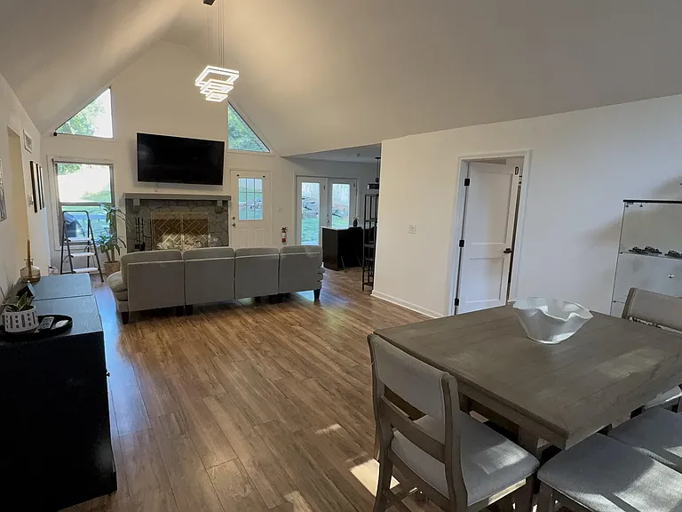 Open-concept living and dining area with vaulted ceilings, large windows, and a fireplaceideal for relaxing and entertaining