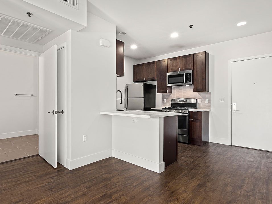 Tiled kitchen with stained wood cabinets and stainless steel appliances.