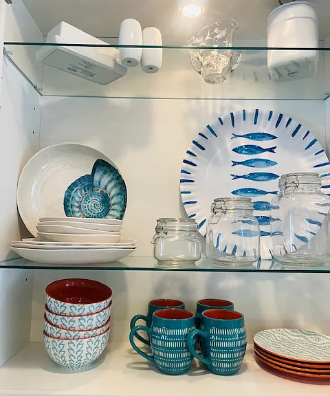 Additional plates, bowls, cups, glassware, and serving dishes in other cabinets and drawers