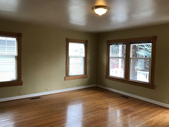 Living room looking north and east. Light-filled, operable insulated window, blinds.