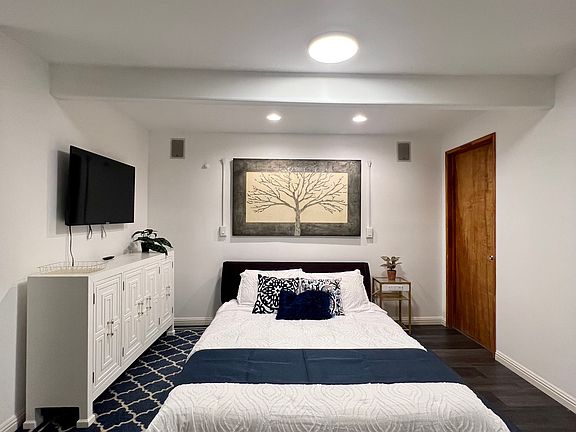 Queen size bed, dresser, and bathroom door.