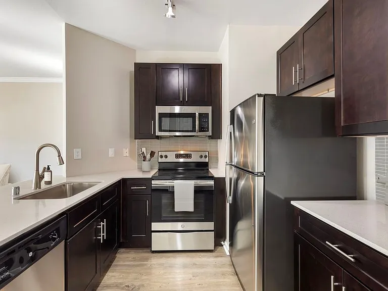 Classic Package I kitchen with stainless steel appliances, tile backsplash, white quartz countertop, espresso cabinetry, and hard surface flooring