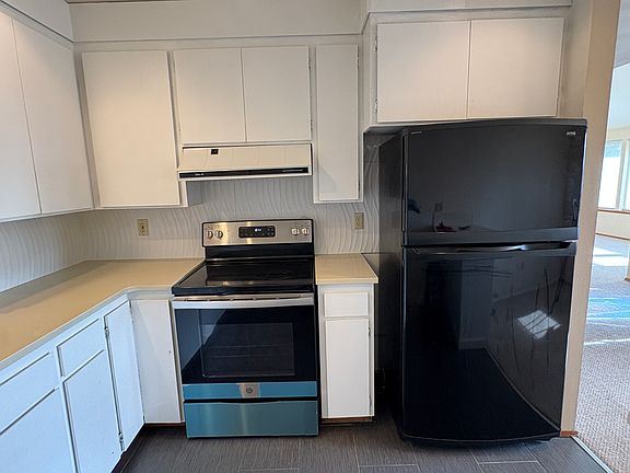 Newer glass top electric range with vent fan to exterior. Freezer top refrigerator with ice maker