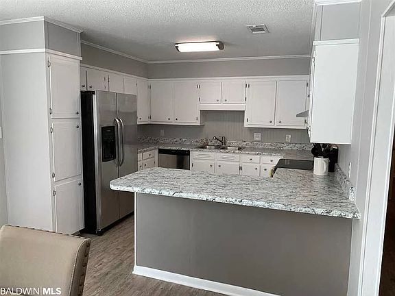 Bright kitchen with plentiful cabinet and countertop space and equipped with stainless appliances