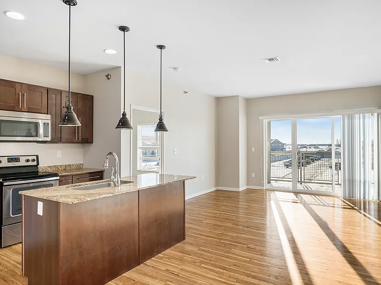 Modern open-concept kitchen and living area with sleek appliances, elegant wooden cabinetry, and large windows offering abundant natural light. Modern open-concept kitchen and living area with sleek appliances, elegant wooden cabinetry, and large windows 