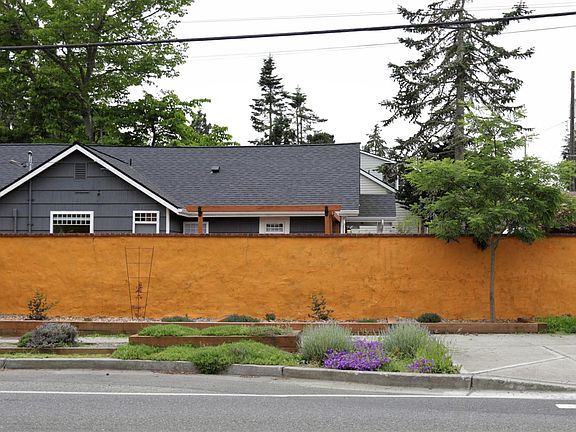 House viewed from 35th Ave SW showing stucco wall and landscaping.