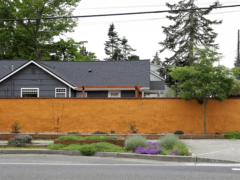 House viewed from 35th Ave SW showing stucco wall and landscaping.