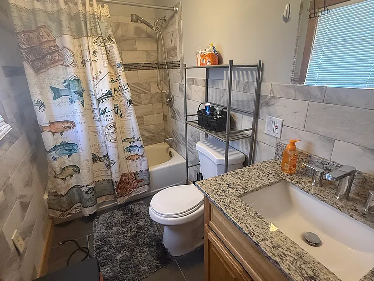 Updated bathroom features tiled tub, granite vanity, and all new fixtures