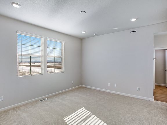 A spacious, well-lit room with large windows overlooking a scenic outdoor landscape, featuring hardw