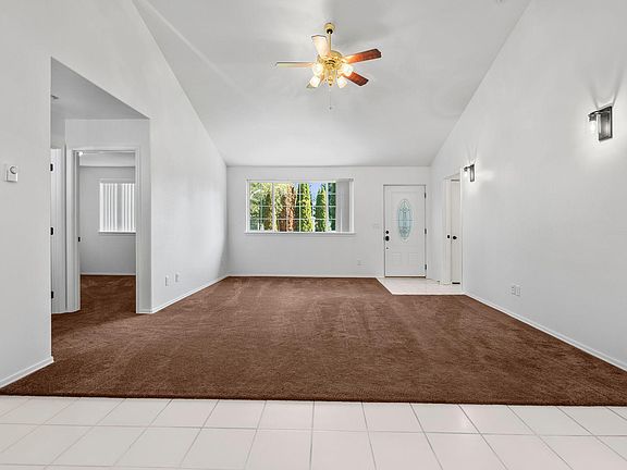 Living room as seen from dining area- Front door straight ahead guest bath and 2 smaller bedrooms to the left- Ceiling fan helps cool the space on warmer day