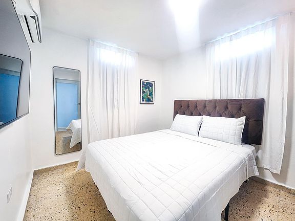 Master bedroom with queen size bed, 43" TV and mini split ac unit.