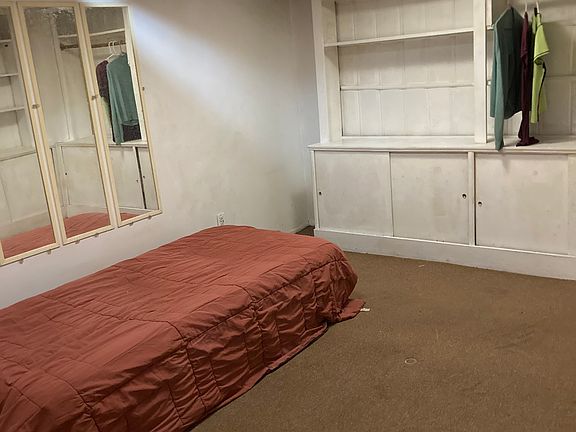 Twin size bed in mirrored bedroom with clothing storage cabinet