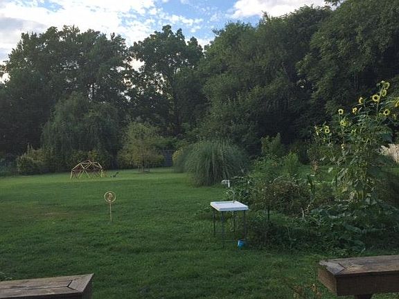 Expansive half acre, fully fenced in back yard, with raised beds (summer view.)