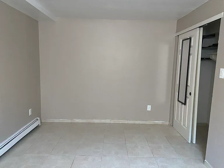 Comfortable bedroom on the second floor featuring durable tile flooring and a spacious closet with sliding doors. A versatile space that can easily accommodate a variety of furniture layouts.