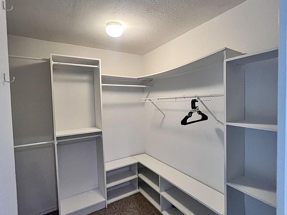 Spacious walk-in closet with built-in shelving, hanging racks, and open cubbies for organized storage.