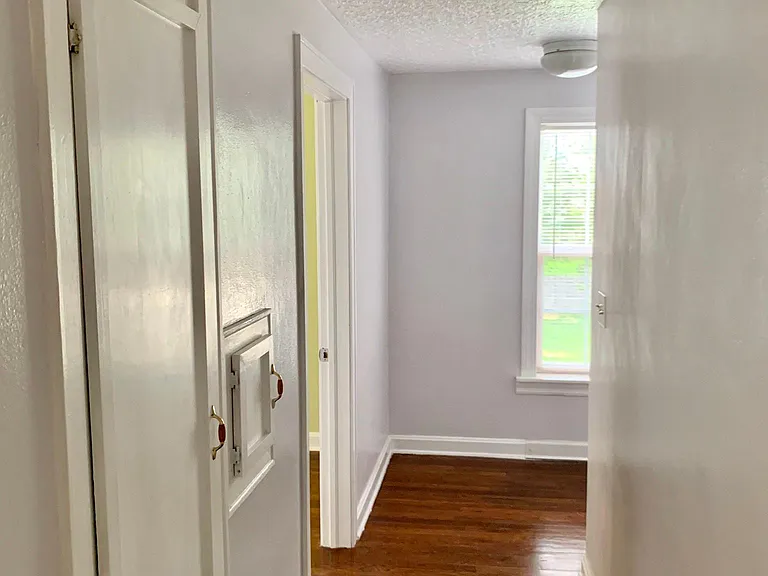 Hallway with laundry shoot by rooms and bath